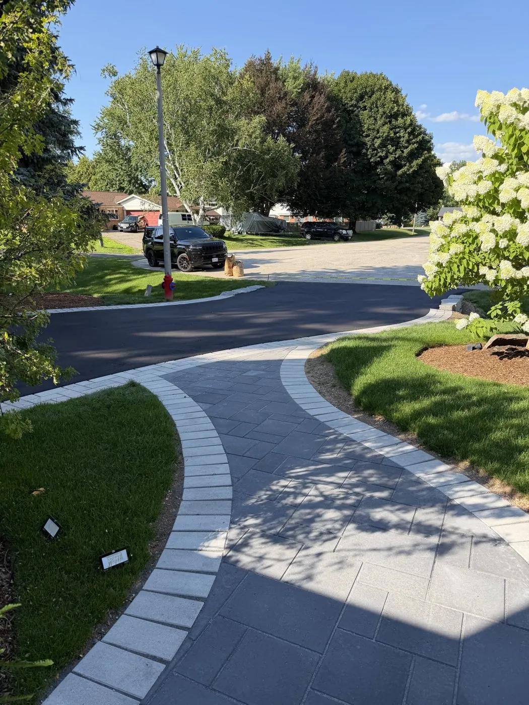 Curved interlock front walkway with a contrasting border leading toward the street in Hamilton