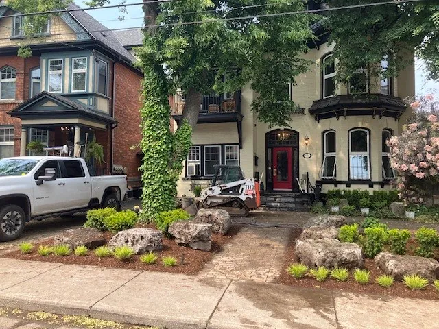 Heritage home frontage with boulder plantings and ornamental grasses along a city street in Hamilton