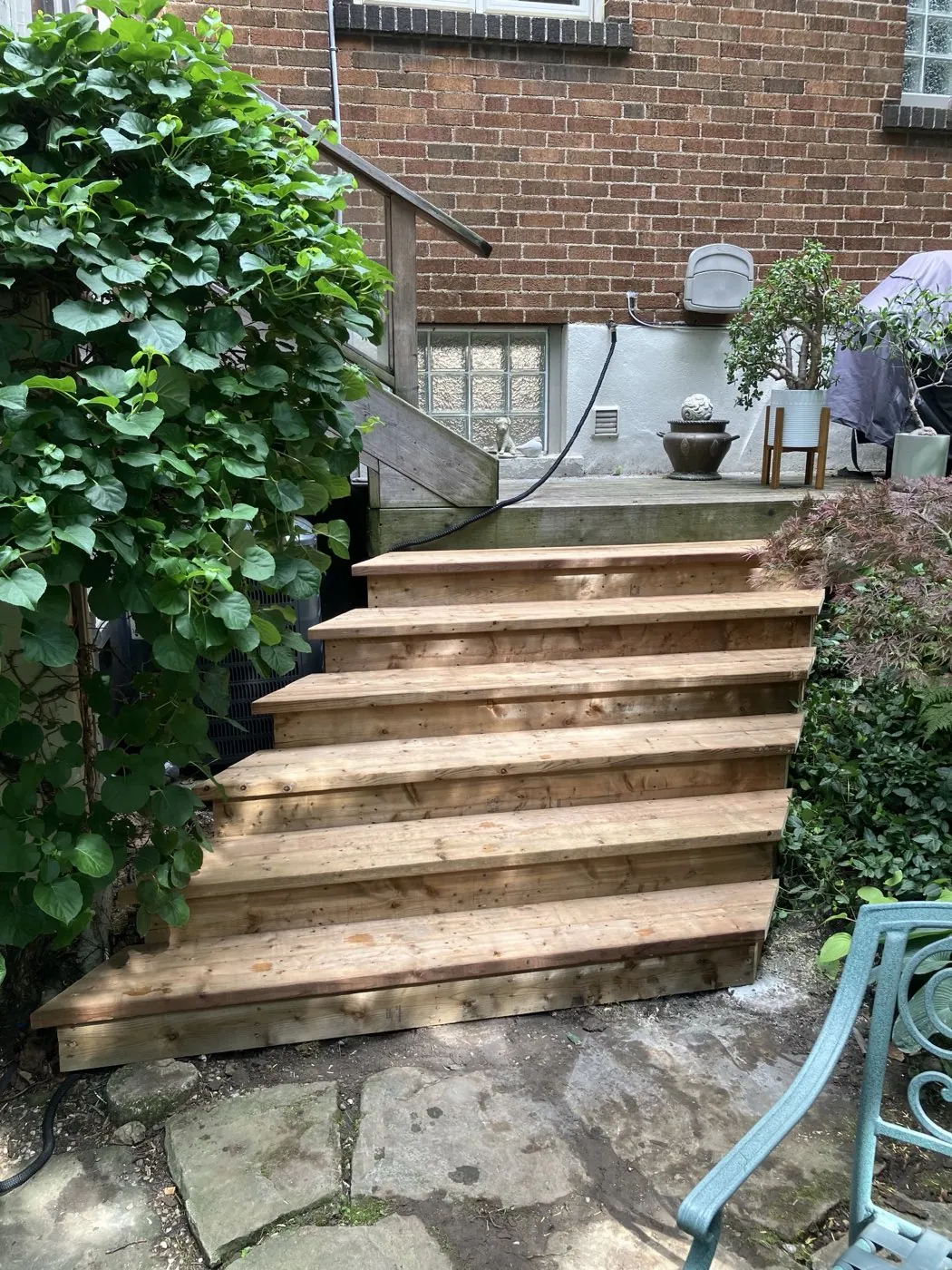 Freshly built wood steps rising to a back landing beside a brick home in Hamilton